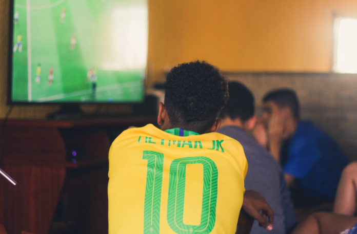 Torcedor de futebol brasileiro assistindo futebol. (Unsplash/Gustavo Ferreira)